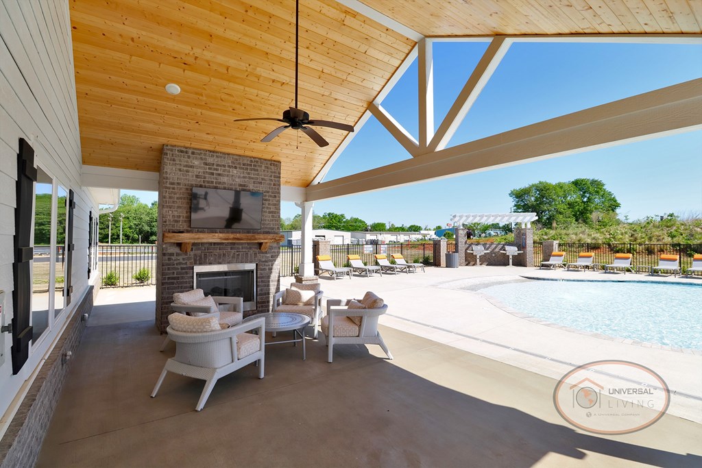 A poolside patio with covered seating area complete with fireplace and flat screen TV.