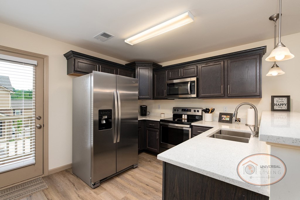 A kitchen with stainless steel appliances and black cabinets.