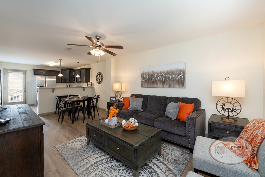 A living room with hardwood vinyl flooring, white walls, and a ceiling fan.