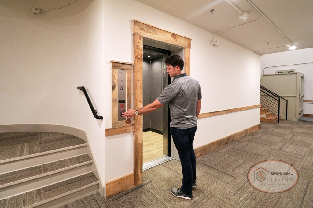 A man pushes a button on the wall as an elevator opens before him.