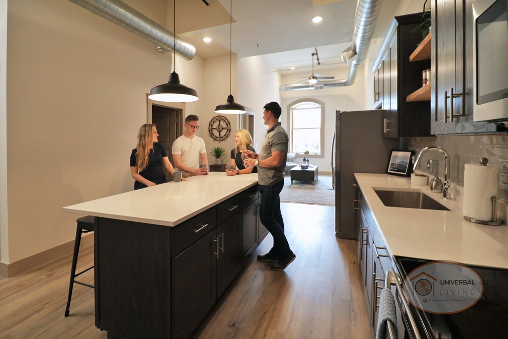 The Henry on Main, Apartment Homes in Downtown Johnson City, Tennessee. A group of friends gathered around a black kitchen island with white countertops.