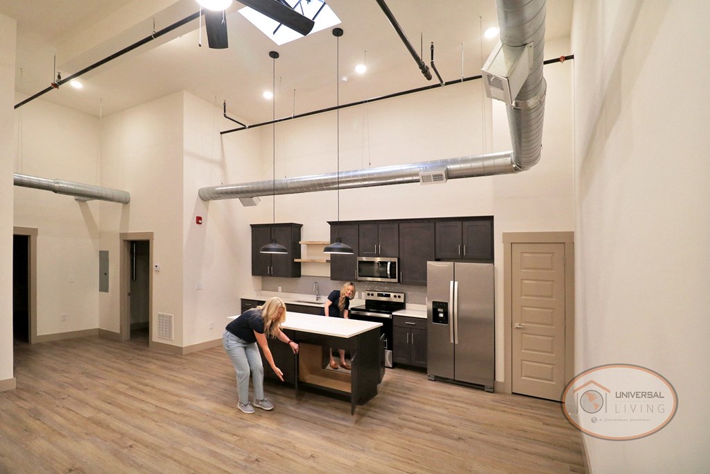 Two women standing in a large, open kitchen, looking into an open kitchen island.
