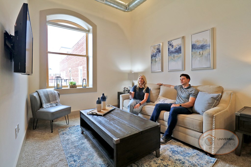 Two people sitting on a couch in a living room watching TV.