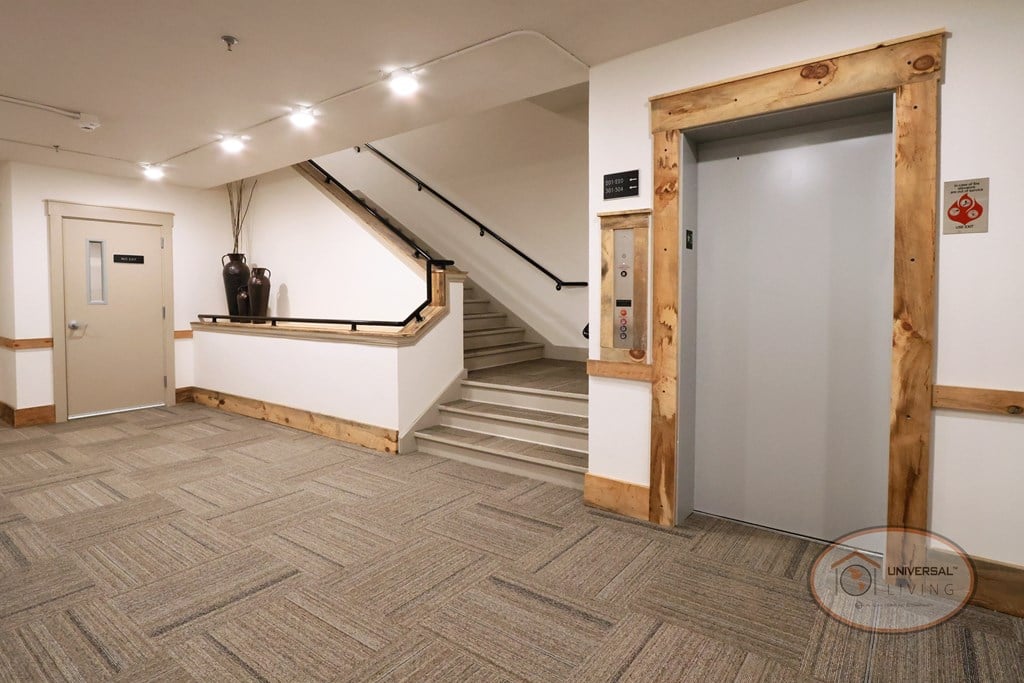 A hallway with a staircase and an elevator.