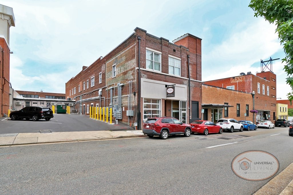 A street view of The Henry on Main with a small, private parking lot to the left of the brick building.
