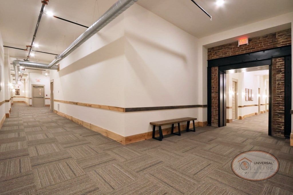 A hallway with a brick accent wall and a bench.