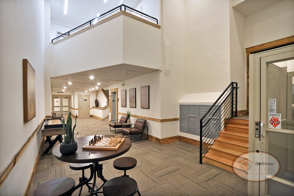 A living room with a staircase and a chess board on the table.