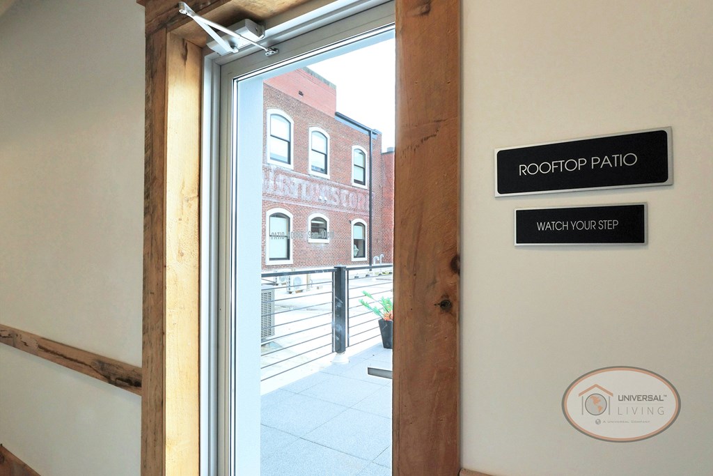 A sign next to a glass door reads "Rooftop Patio."