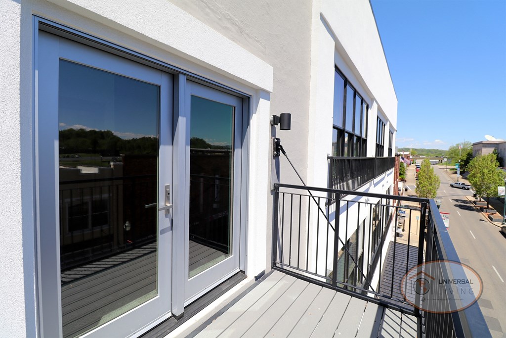 A balcony with a view of the street and mountains in the distance.