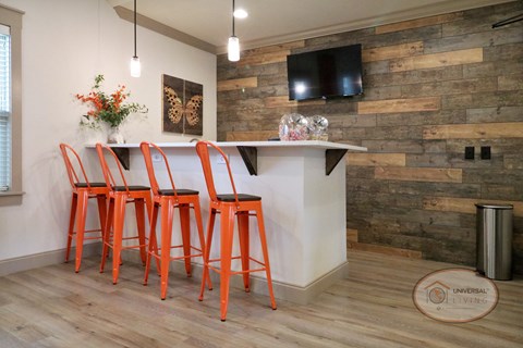 A kitchen with a white counter and orange bar stools.