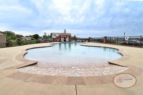 A zero entry pool with lounge chairs and apartments in the background.