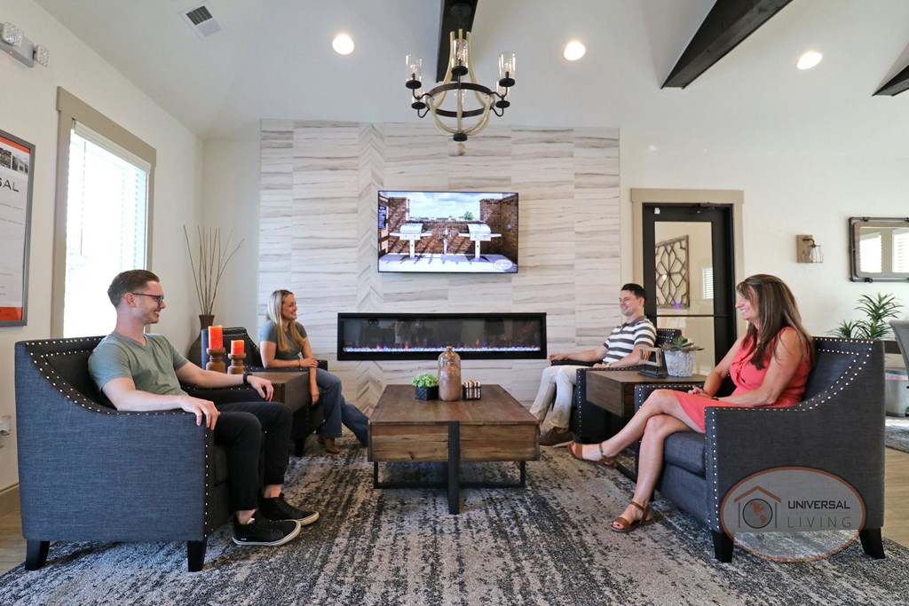 A group of people sitting around the fireplace in the clubhouse.
