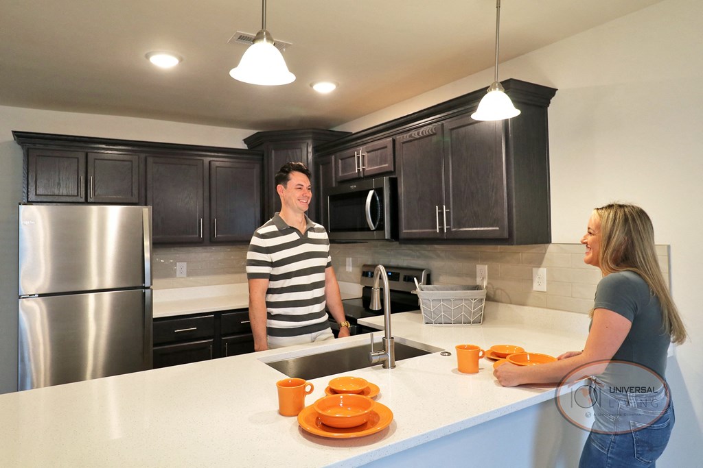 A man and a woman standing in a kitchen talking.