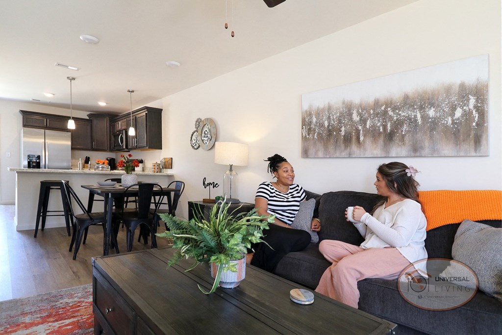 two women sitting on a couch in a living room in an apartment