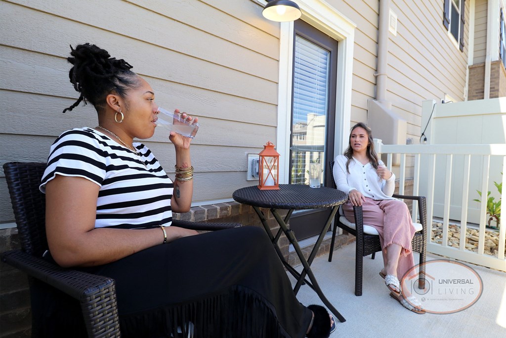 Two women sitting on a patio talking.