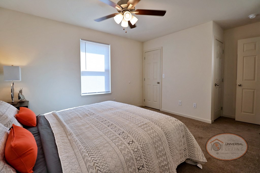 A bedroom with a large bed and a ceiling fan.