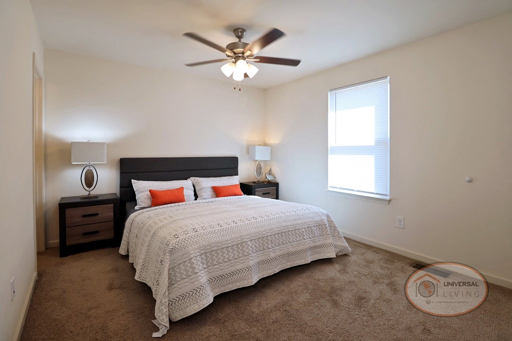 A bedroom with a bed, nightstand, and window.