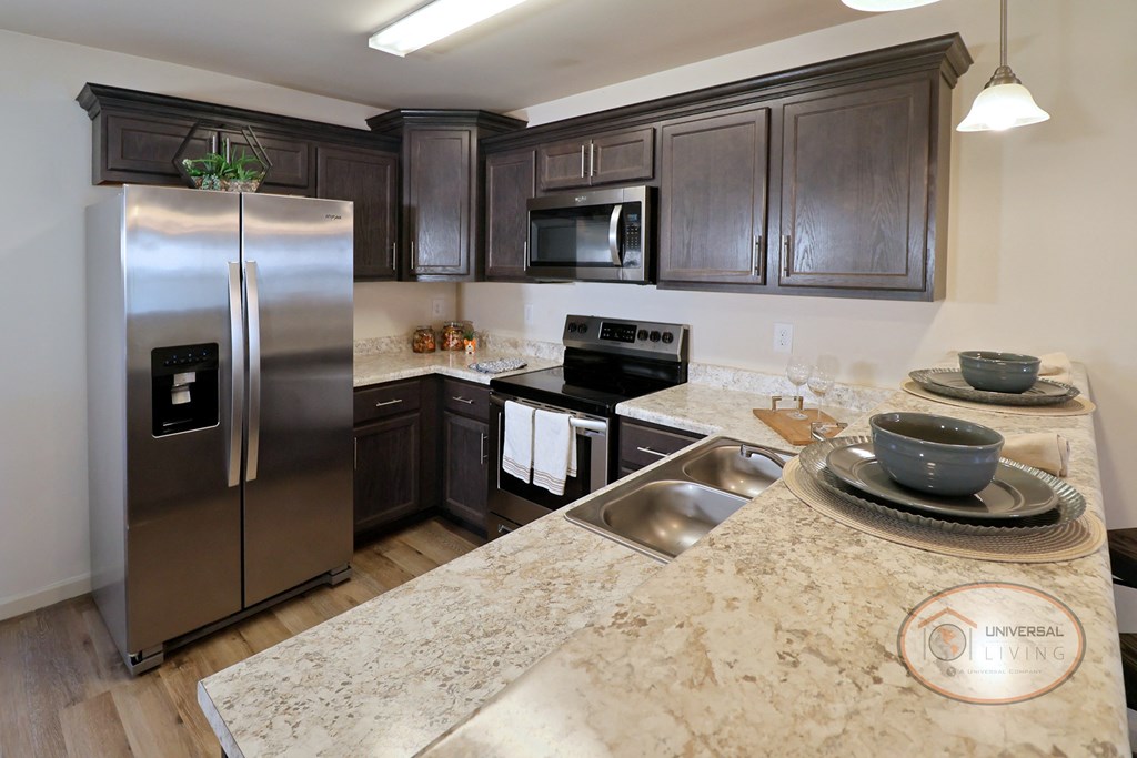 A kitchen with a refrigerator, microwave, oven, and sink.