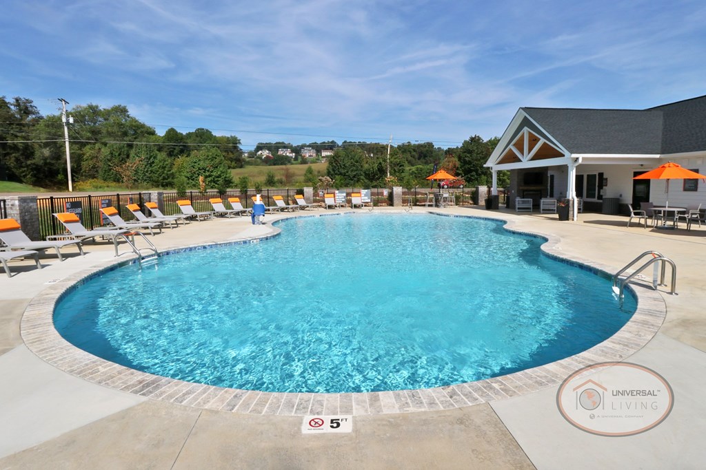 A view of the swimming pool from the 5 foot deep end with lounge chairs and the clubhouse in the background.