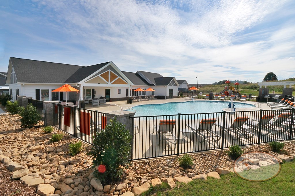 A landscape view of the clubhouse and pool surrounded by fencing.