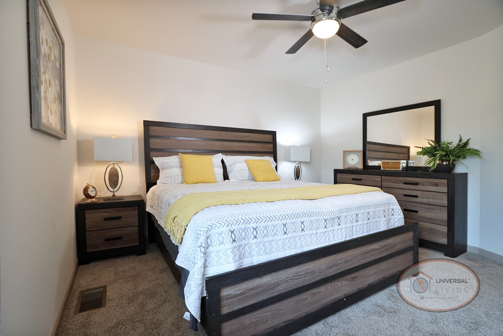 A bedroom with a queen size bed, carpet, and a ceiling fan.