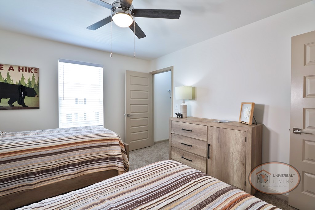 A bedroom with two twin beds, a large window, and walk in closet.