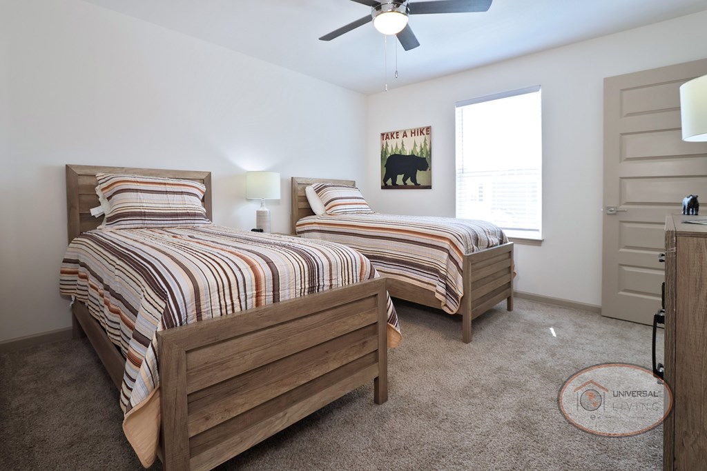 A bedroom with two twin beds, carpet, and a ceiling fan.