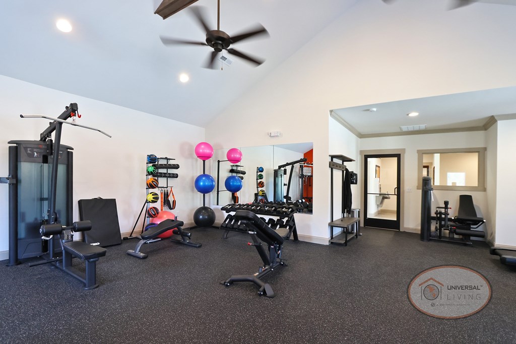 A fitness center with weight training and cardio equipment in front of a mirrored wall.