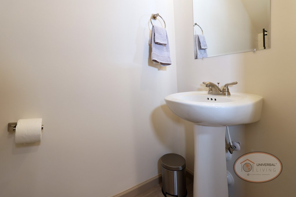 A white sink in a bathroom with a mirror and towel rack.