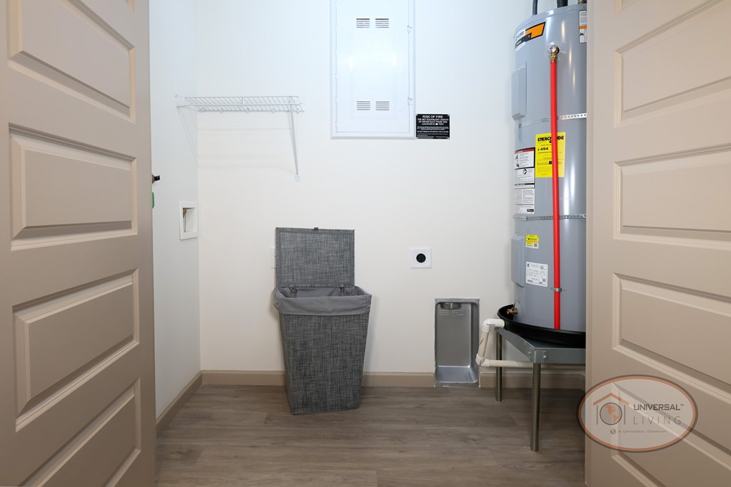 A laundry room with washer and dryer hookups, water heater, and clothes bin.