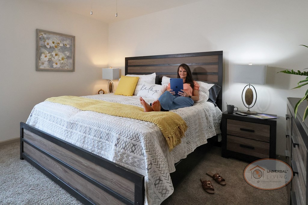 A woman relaxing on a bed, looking at an IPad.