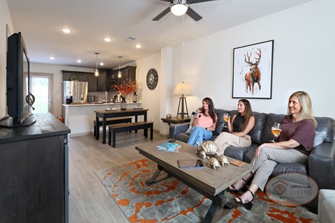 Four women are sitting on a couch in a living room.