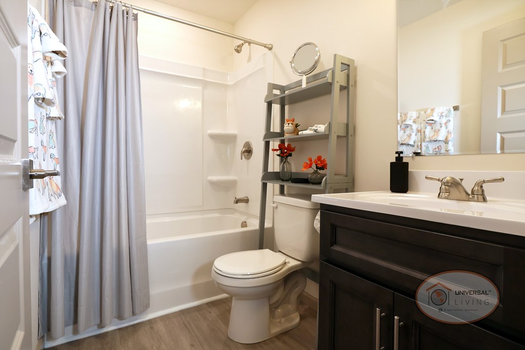 A full bathroom with shower over tub, toilet, dark cabinets, and sink.