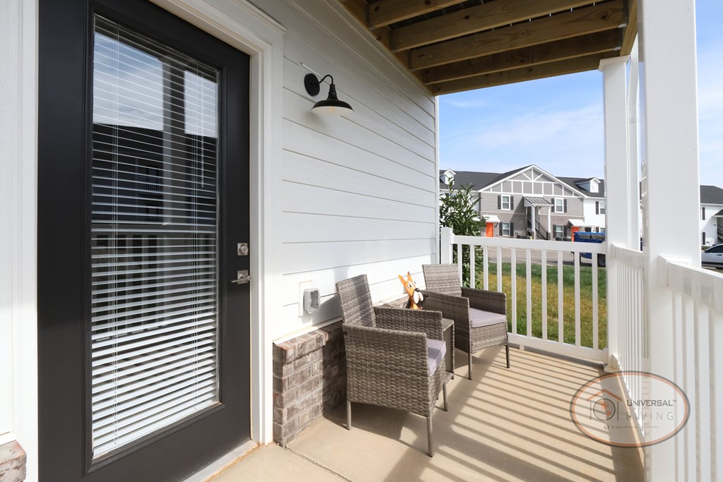 A fenced in patio with lounge seating and a glass door leading into the home.