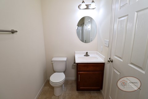 A bathroom with a toilet, sink and mirror.