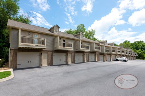 A tan row of apartments with balconies and drive-under garages.