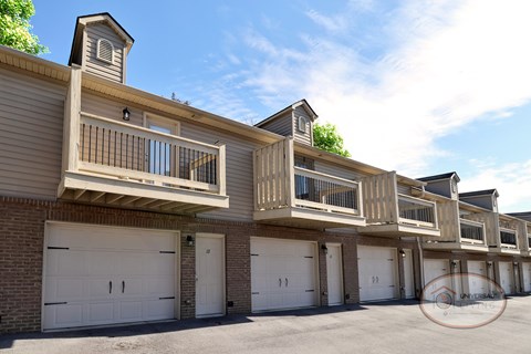 A close up image of the row of tan apartment homes with garages and balconies.
