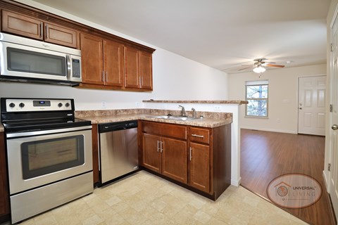 A kitchen with stainless steel appliances, a bar top, and dark wooden cabinets.