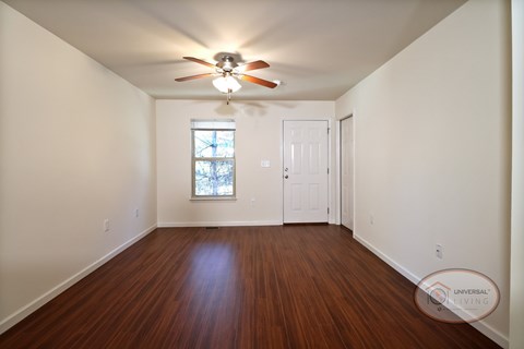 The living room with vinyl hardwood flooring, white walls, and a ceiling fan.