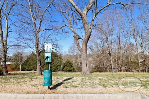 A pet waste pick-up station on a grassy flat area.