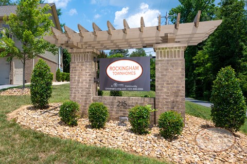 A sign for Rockingham Townhomes is displayed in front of a landscaped area.
