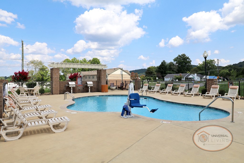 A swimming pool with lounge chairs and apartment buildings in the background.
