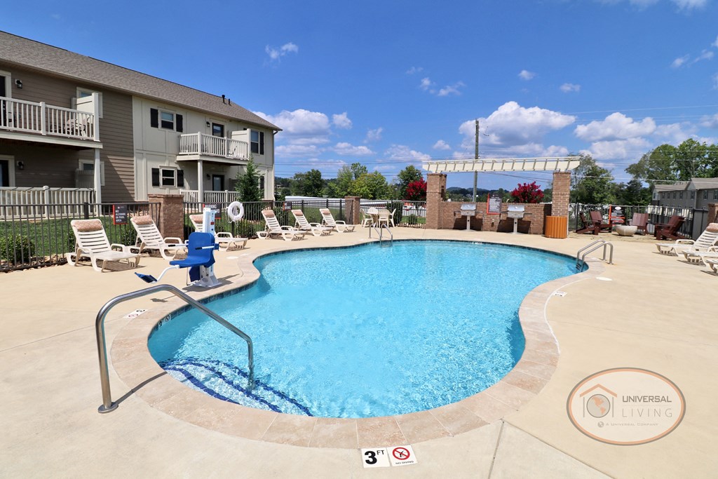 A swimming pool with lounge chairs and apartment buildings in the background.