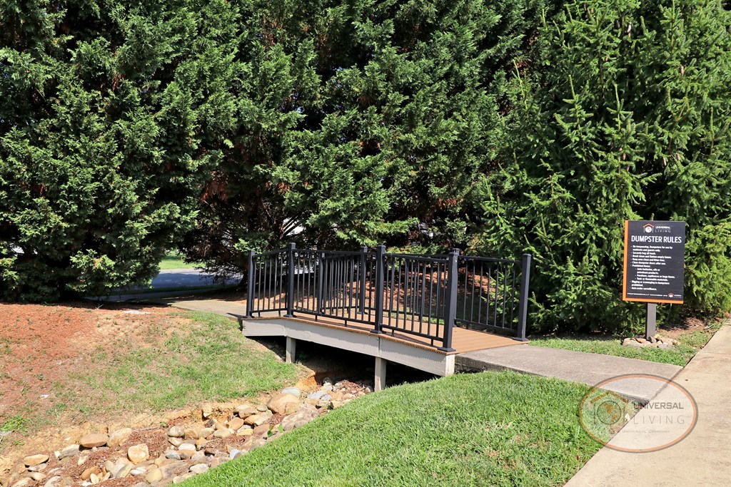 a bridge over a creek in a park with a sign