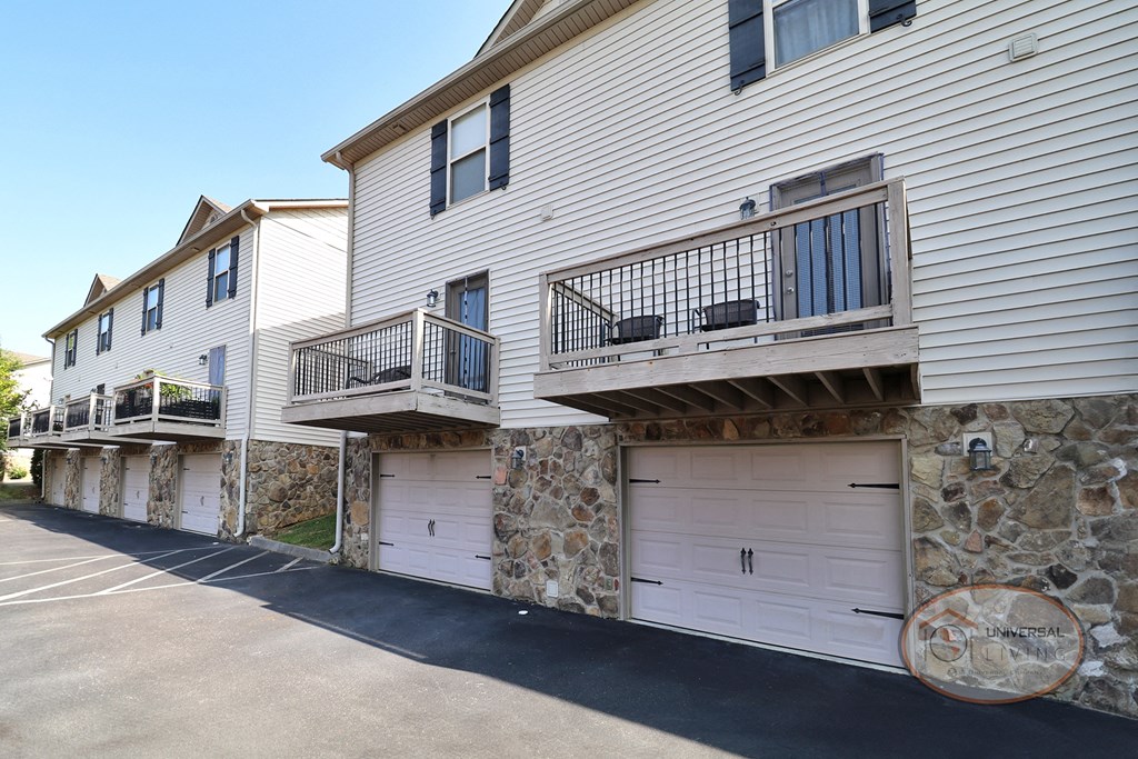 a white house with two balconies and two white garage doors