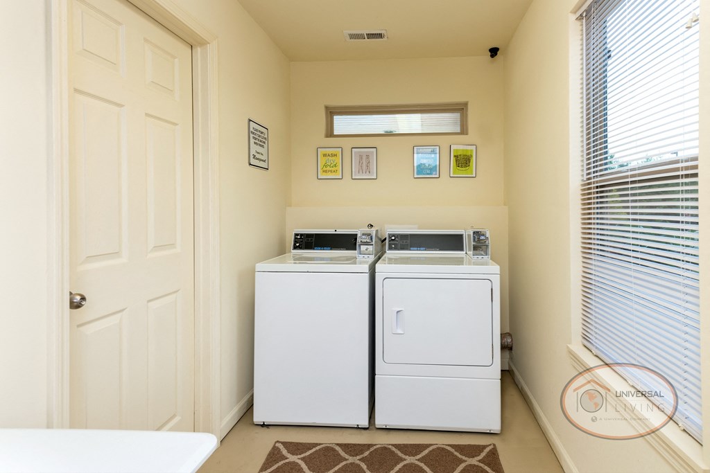 a laundry room with two washer and dryers and a window and a door