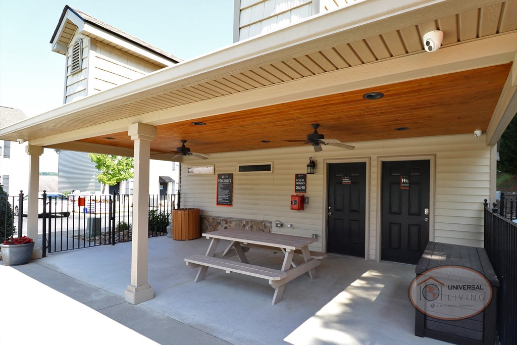 a covered patio with a picnic table and a grill