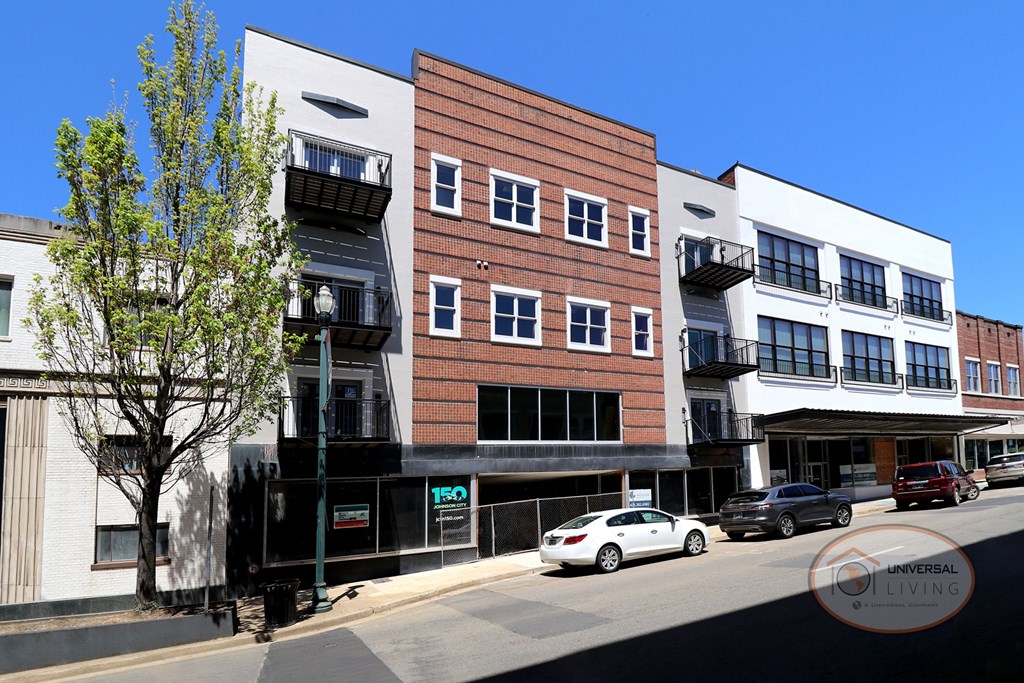 The Henry on Main, Apartment Homes in Johnson City, Tennessee. The front of a white and brick downtown apartment complex with balconies and large windows.