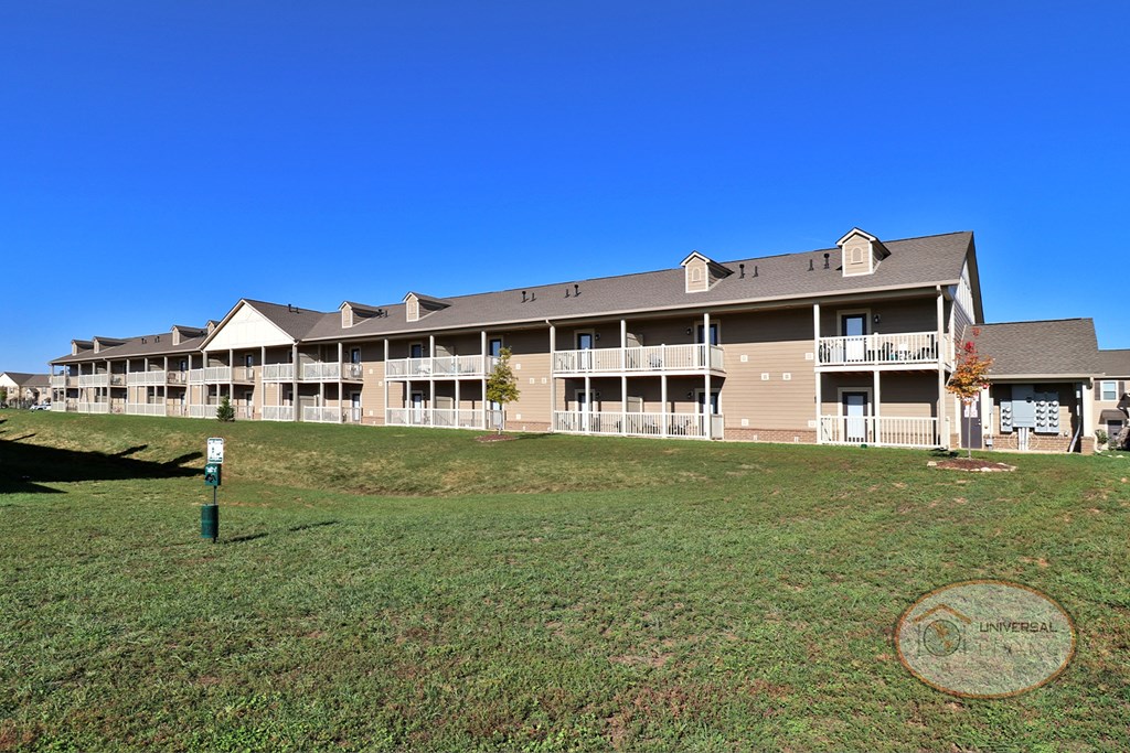 The rear of a large one bedroom stacked apartment home with patios and balconies.
