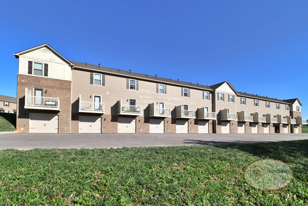 The rear of a row of two and three bedroom apartment homes with balconies and garages.